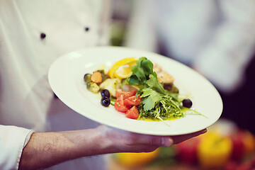 Image showing Chef hands holding dish of fried Salmon fish fillet