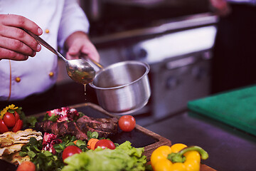 Image showing Chef hand finishing steak meat plate