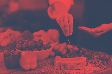 Image showing Chef putting salt on juicy slice of raw steak