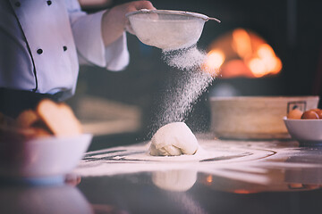 Image showing chef sprinkling flour over fresh pizza dough