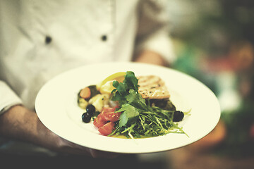 Image showing Chef hands holding dish of fried Salmon fish fillet