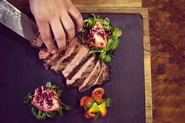 Image showing top view of Chef hands serving beef steak