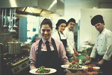 Image showing young waitress showing dishes of tasty meals