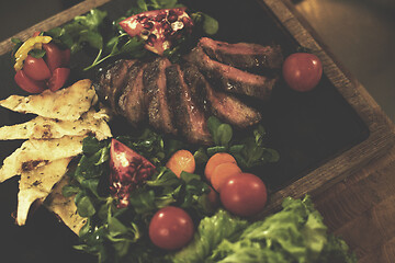 Image showing Juicy slices of grilled steak on wooden board