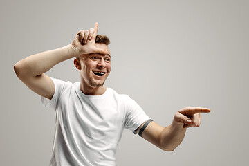 Image showing Losers go home. Portrait of happy guy showing loser sign over forehead