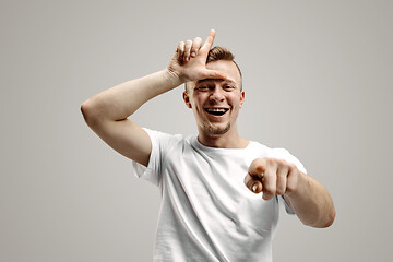 Image showing Losers go home. Portrait of happy guy showing loser sign over forehead