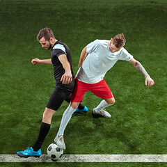 Image showing Football players tackling ball over green grass background