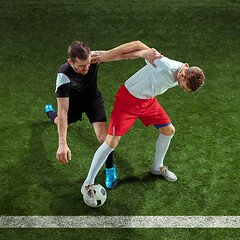 Image showing Football players tackling ball over green grass background