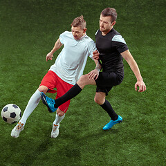 Image showing Football players tackling ball over green grass background