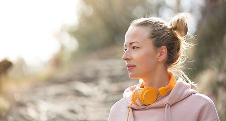 Image showing Portrait of beautiful sports woman with hoodie and headphones during outdoors training session.