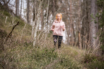 Image showing Active sporty woman listening to the music while running in autumn fall forest. Female runner training outdoor. Healthy lifestyle image of young caucasian woman jogging outside