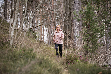 Image showing Active sporty woman listening to the music while running in autumn fall forest. Female runner training outdoor. Healthy lifestyle image of young caucasian woman jogging outside