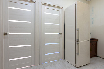 Image showing Two interior doors in the apartment, there is a refrigerator on the right