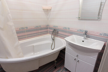 Image showing Interior of a cozy ordinary bathroom with a washbasin, a bathtub and a mirror