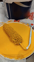 Image showing Paint roller with orange paint.