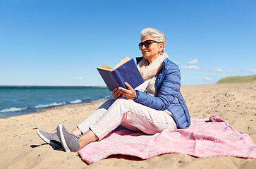 Image showing happy senior woman reading book on summer beach