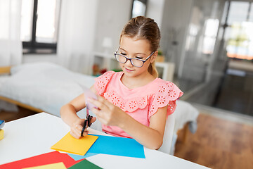 Image showing girl cutting color paper with scissors at home