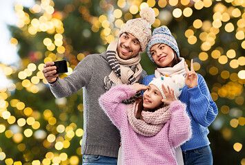 Image showing happy family taking selfie over christmas lights