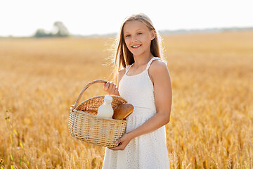 Image showing girl with bread and milk in basket on cereal field