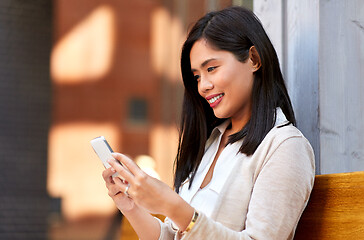 Image showing asian woman using smartphone sitting on bench