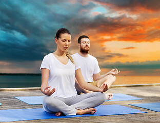 Image showing couple meditating in yoga lotus pose outdoors