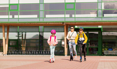 Image showing happy school children with mother riding scooters