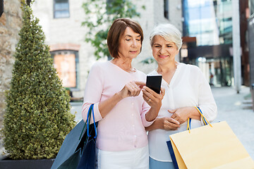 Image showing old women with shopping bags and cellphone in city