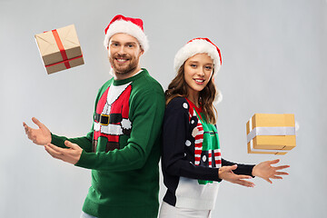 Image showing happy couple in christmas sweaters with gifts