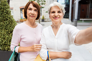 Image showing old women with shopping bags taking selfie in city