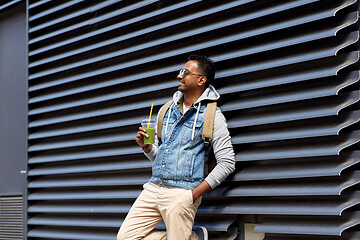 Image showing man with backpack drinking smoothie on street