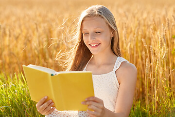 Image showing smiling young girl reading book on cereal field