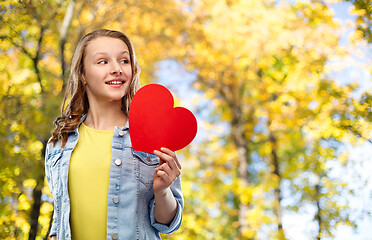 Image showing smiling teenage girl with red heart in autumn park