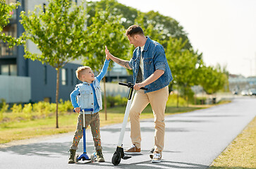 Image showing father and son with scooters making high five