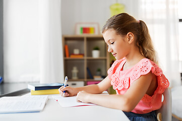 Image showing student girl with book writing to notebook at home