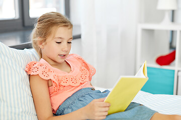 Image showing happy little girl reading book at home