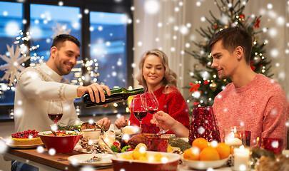 Image showing happy friends drinking red wine at christmas party