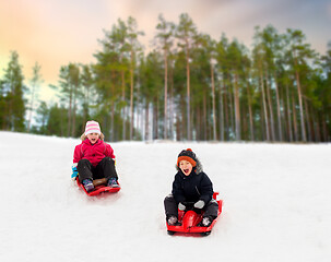 Image showing happy kids sliding on sleds down hill in winter