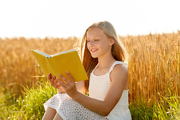Image showing smiling young girl reading book on cereal field