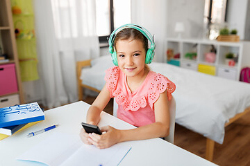 Image showing girl in headphones listening to music on cellphone