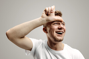 Image showing Losers go home. Portrait of happy guy showing loser sign over forehead