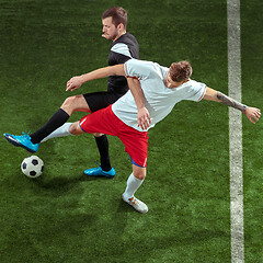 Image showing Football players tackling ball over green grass background