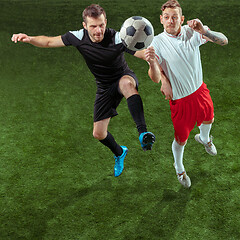 Image showing Football players tackling ball over green grass background