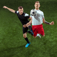 Image showing Football players tackling ball over green grass background