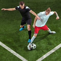 Image showing Football players tackling ball over green grass background