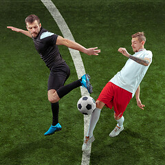 Image showing Football players tackling ball over green grass background