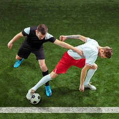 Image showing Football players tackling ball over green grass background