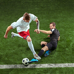 Image showing Football players tackling ball over green grass background