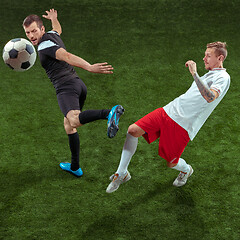 Image showing Football players tackling ball over green grass background