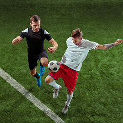 Image showing Football players tackling ball over green grass background