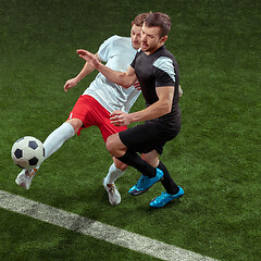 Image showing Football players tackling ball over green grass background